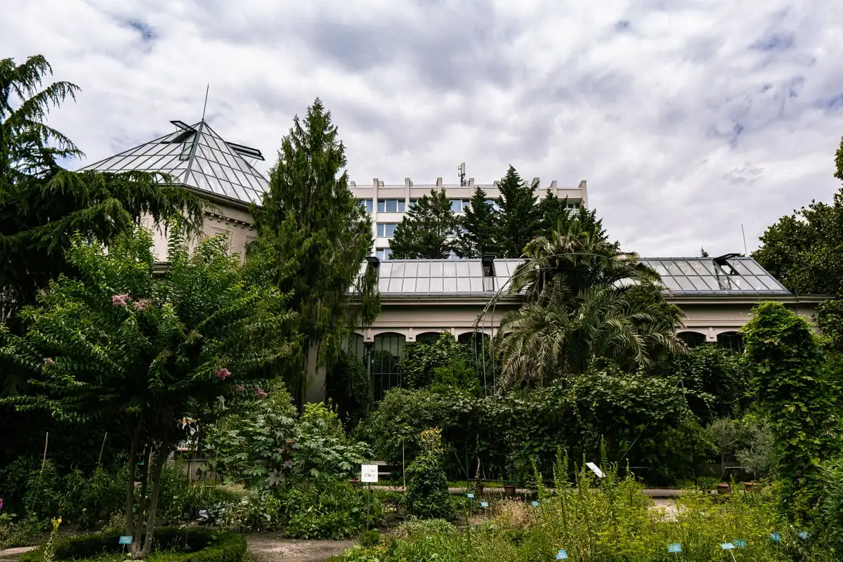 Jardin public avec végétation abondante et sentiers ombragés en milieu urbain