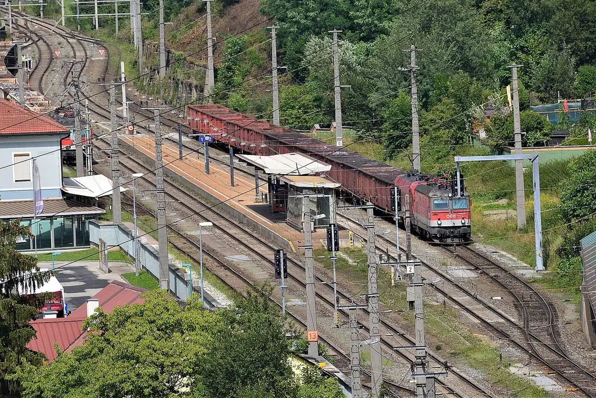 Gare de banlieue avec train et quais, symbolisant accès aux pôles d'emploi